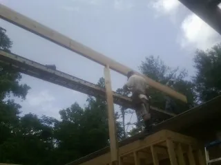Carpenter setting a ridge beam over a new addition frame in Kinzers
