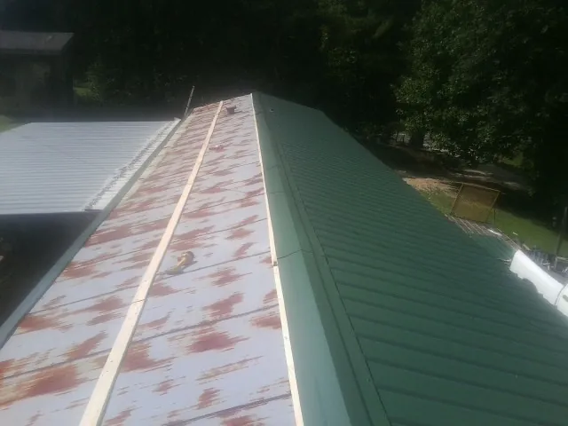 Old rusted panels beside newly installed green metal roofing — Wind Damage Roof Repair by Roofing Brothers in Kinzers