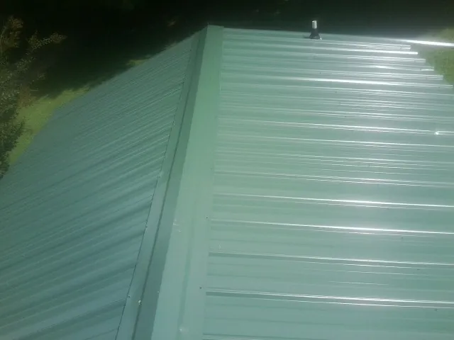 New green metal panels meeting at the ridge of a roof — Flat Roof Repair work by our crew in Kinzers