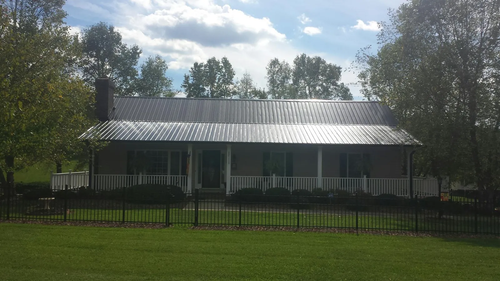 Gray metal roof on a brick ranch with a full width front porch — Gutter Guard Installation work by our crew in Kinzers