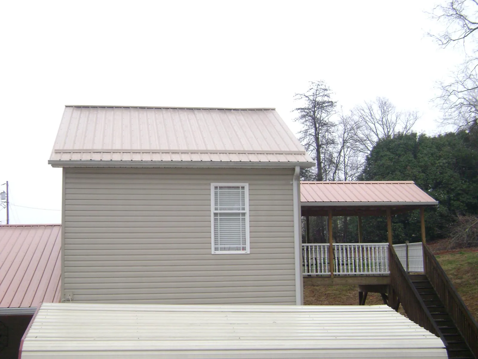 Tan metal roofs on a two story addition and attached porch, from a Roof Replacement job in Kinzers