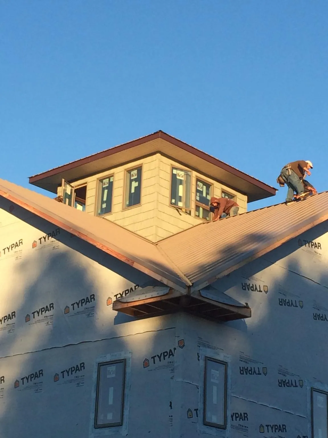 Roofers working around a rooftop cupola on a new metal roof at sunset — Roof Waterproofing in Kinzers by Roofing Brothers